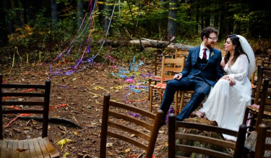 A bride and group sitting together in the woods.