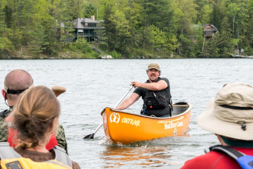 A man in a canoe speaking to a group.