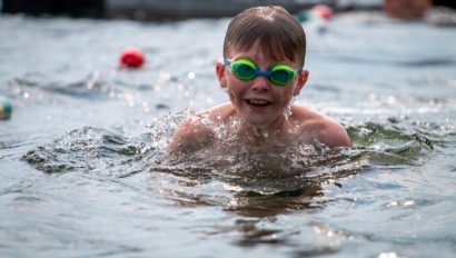 A young camper wearing goggles, swimming.