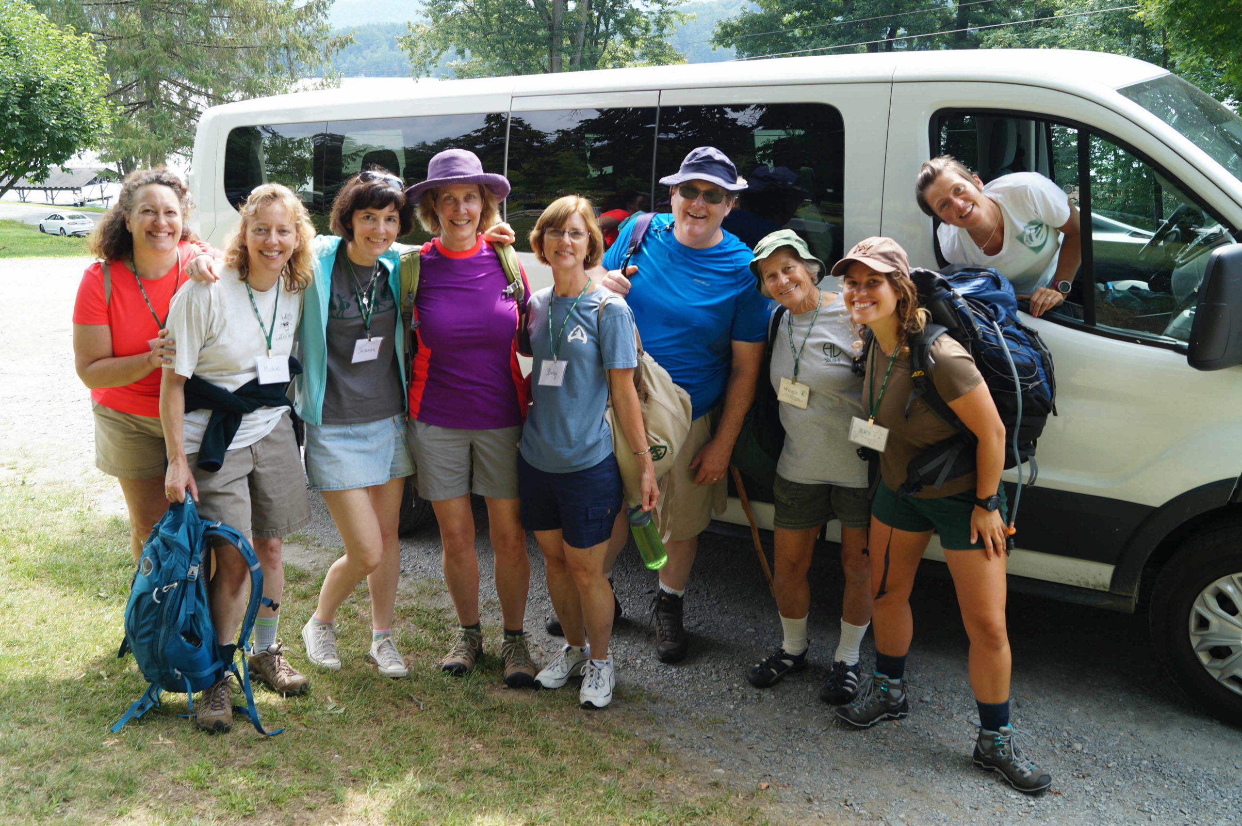 Camp alum standing outside a van in hiking clothes.