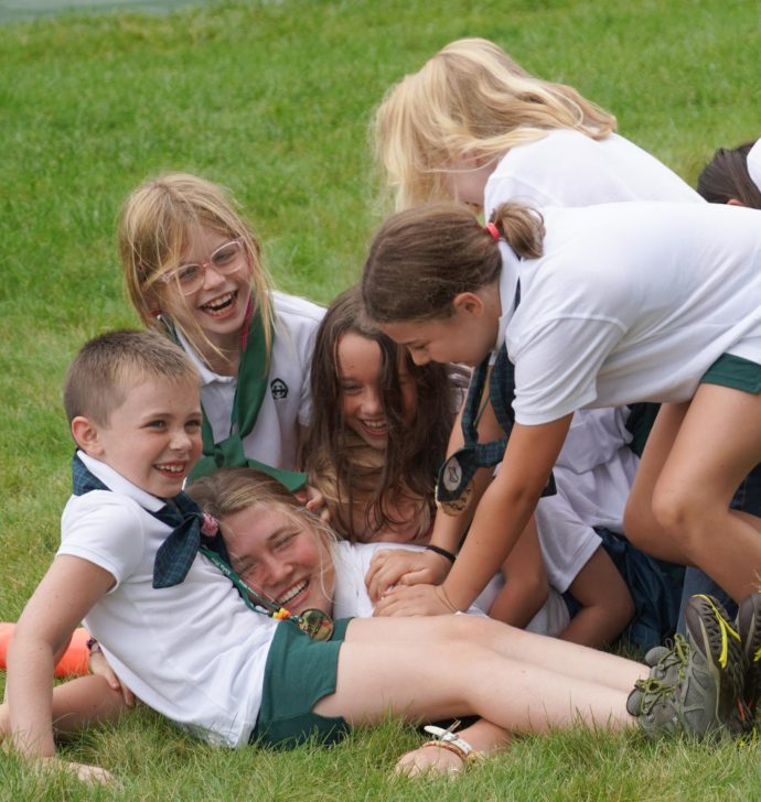 Campers laughing and piling on a counselor.