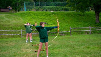 Campers shooting a bow and arrow.