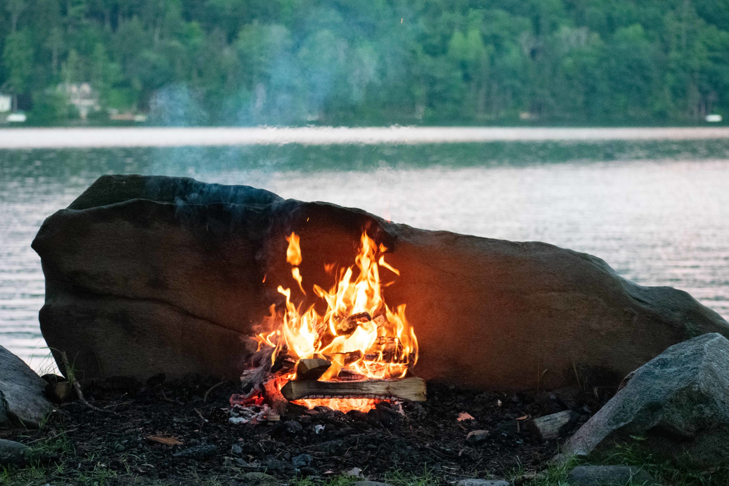 A campfire with a lake in the background.