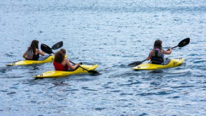 Three campers kayaking on a lake.