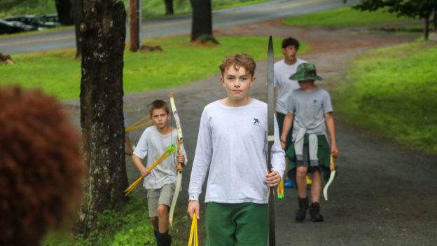 Campers walking with bows and arrows.
