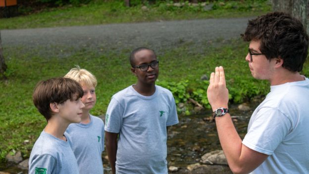 A counselor talking to campers by the Lanakila brook.
