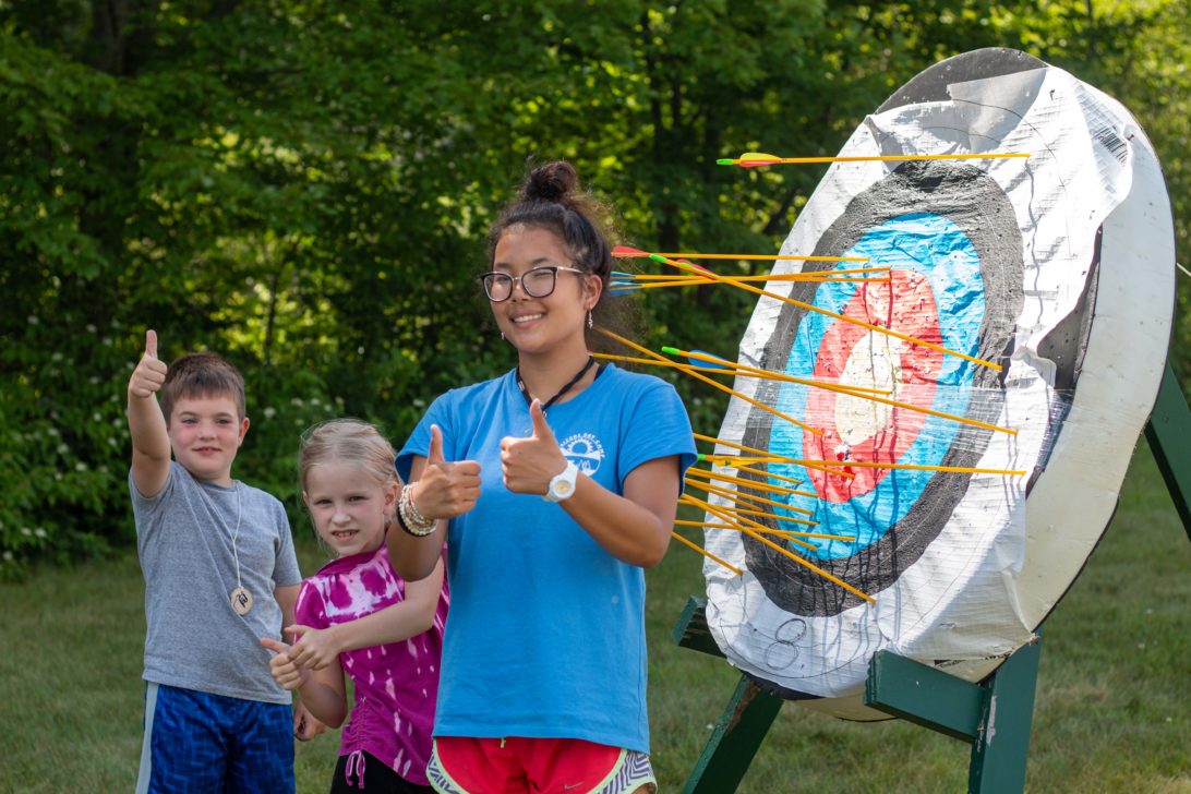 Campers posing in front of a archery target.