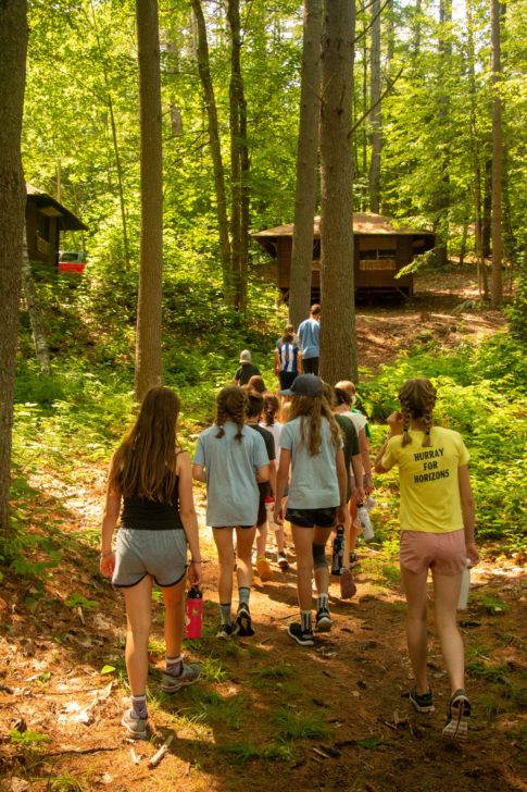 Campers walking through a forest.