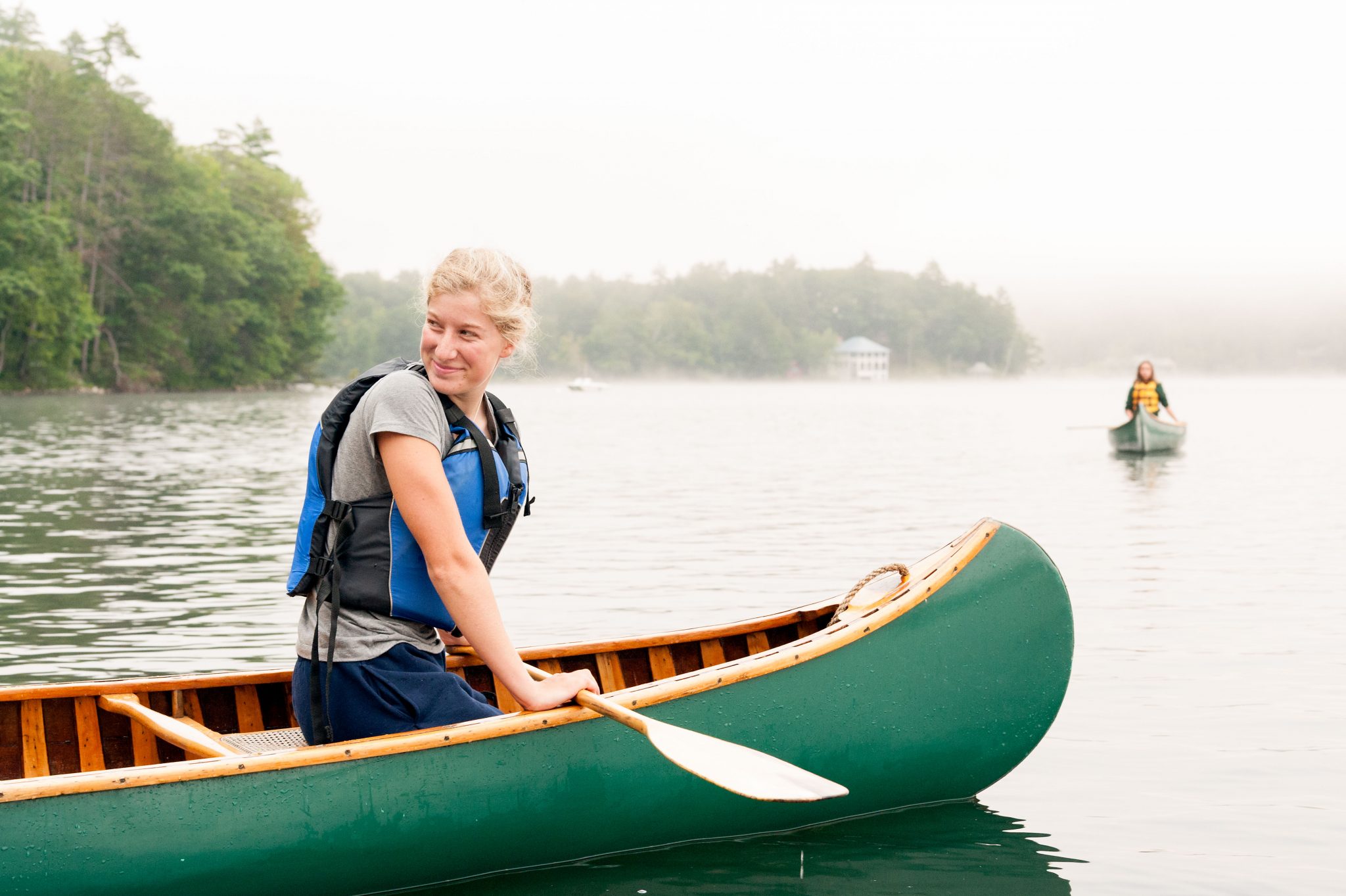 An Aloha camper smiling in a canoe on the lake.