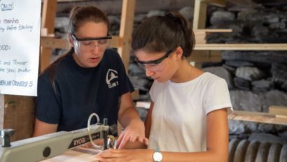 A camper working in the woodshop with an counselor's guidance.