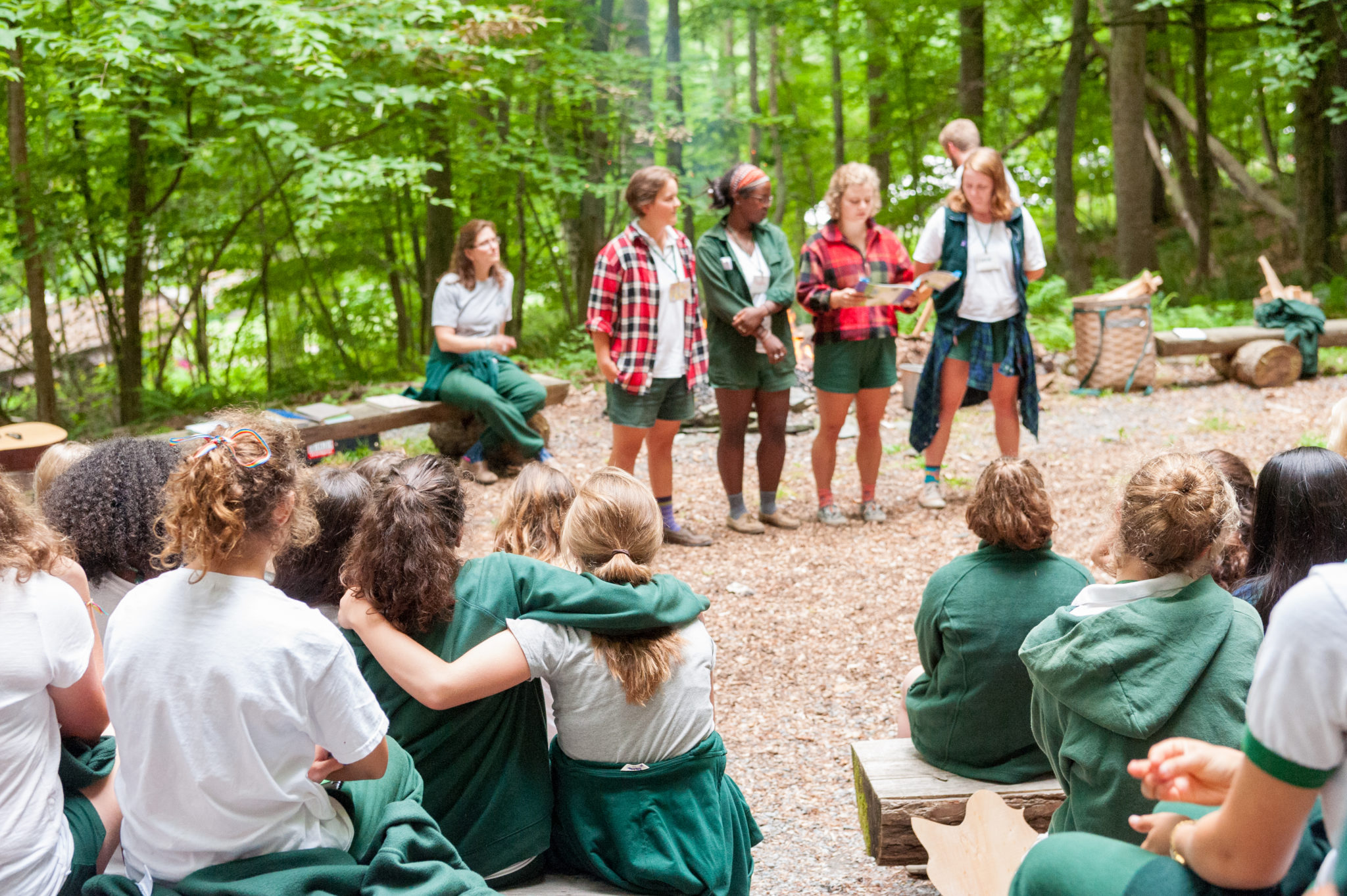 A group of counselor reading to the camp at a special spot in the Aloha woods called wedding ring.