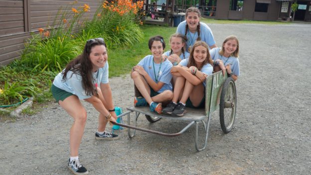 Campers sitting in a wheelbarrow.