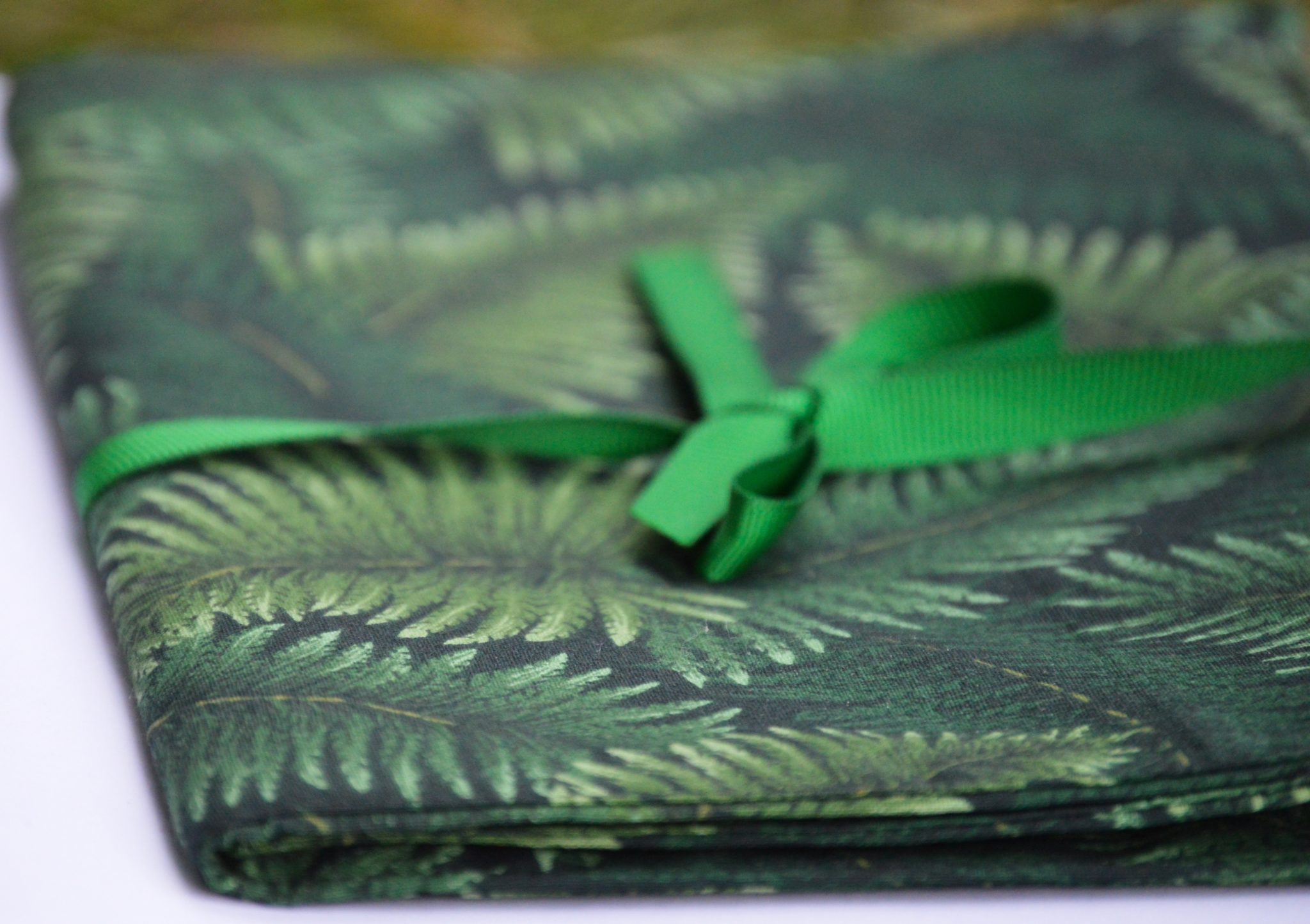 A bolt of green fern fabric with a ribbon tied around it.