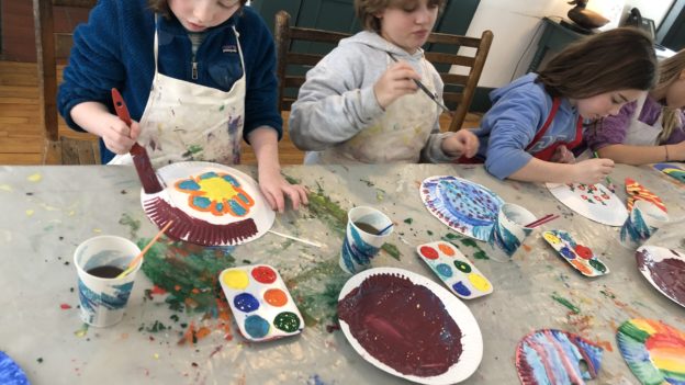 Campers painting on paper plates.