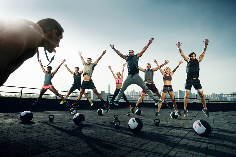 A fitness trainer overseeing a group doing jumping jacks.