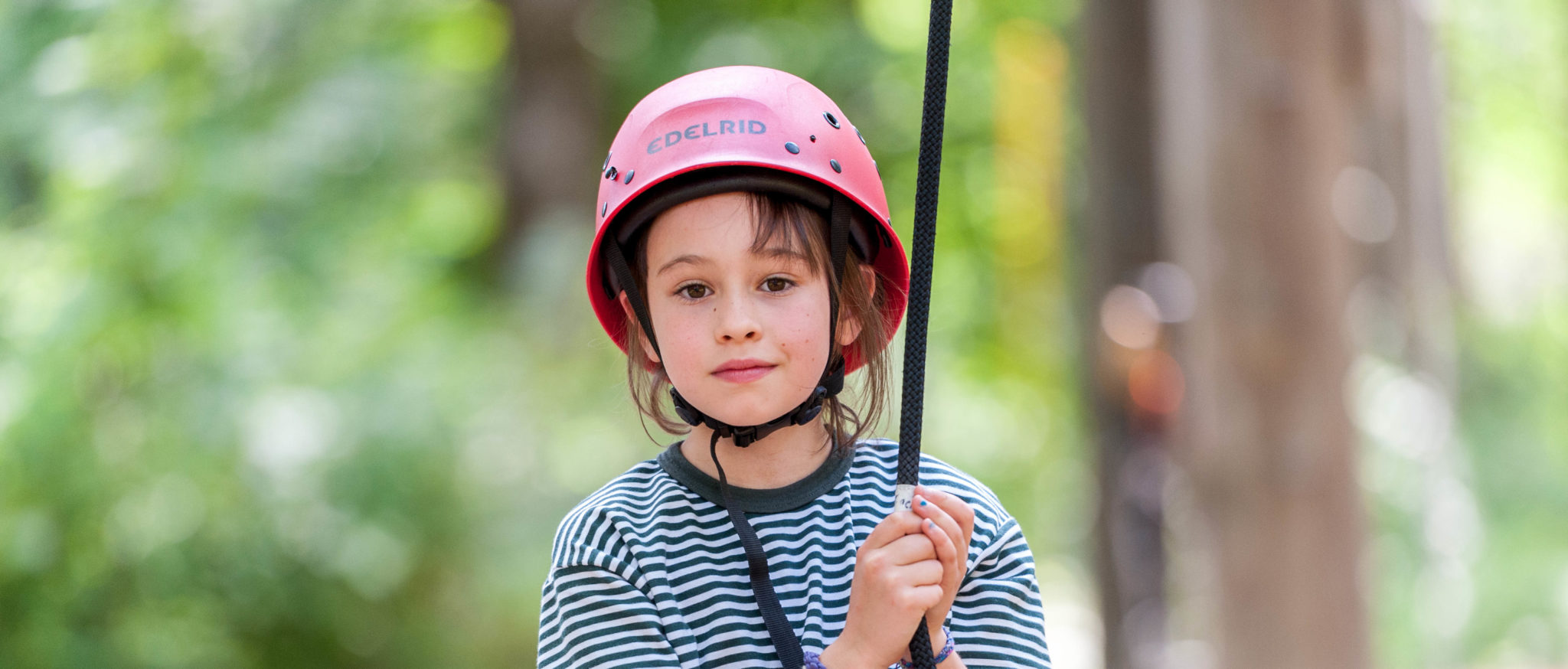 A Hiver in a red helmet with a rope on the ropes course.