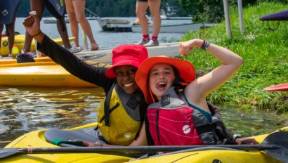 Two campers on their own kayaks, posing together.