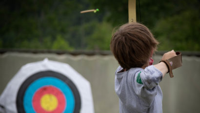 A camper shooting an arrow towards a target.