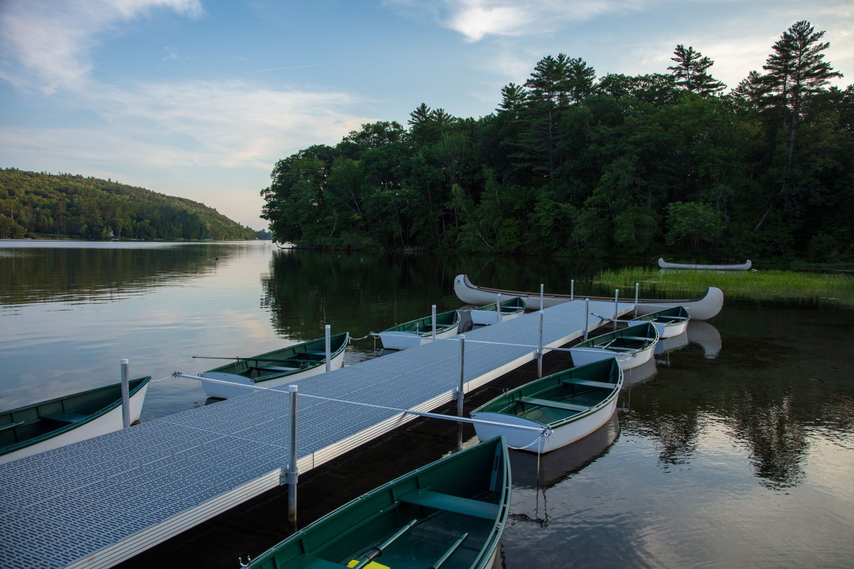 A bunch of row boats next to the docks on the lake.