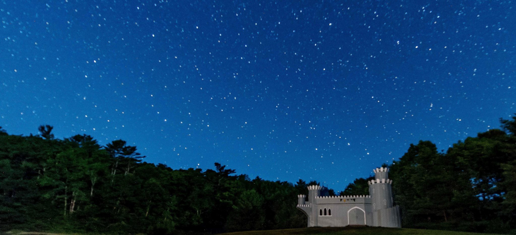 Lanakila's blue wooden castle underneath a nightsky full of stars.
