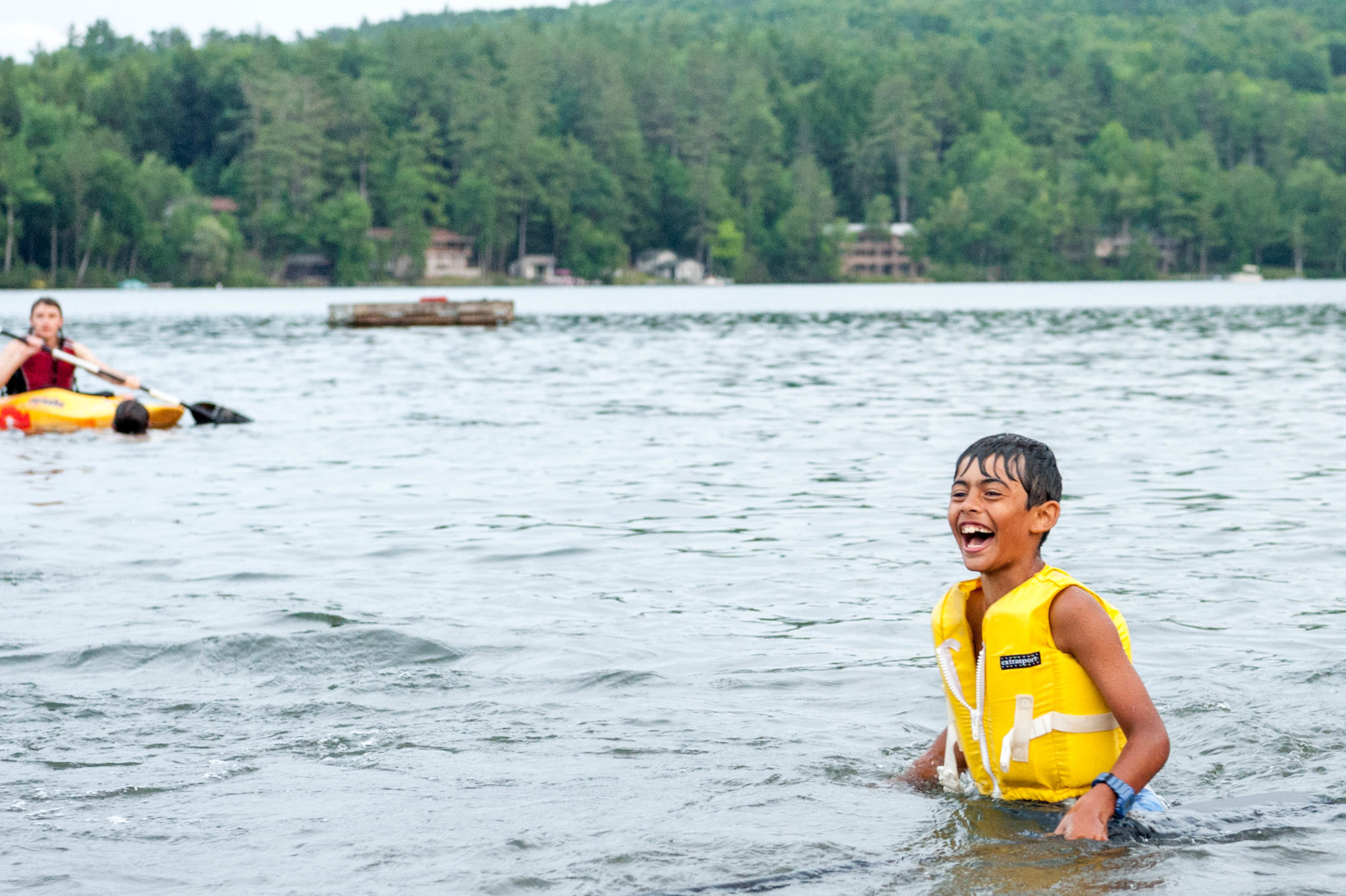 A Lanakila camper laughing in the lake with a PDF on.