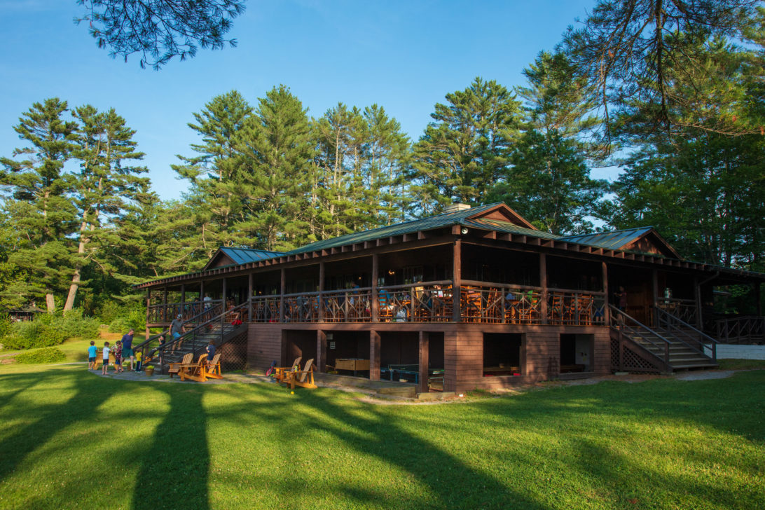 The Ohana dining hall - a rustic looking wooden building with a porch surrounded by grass.