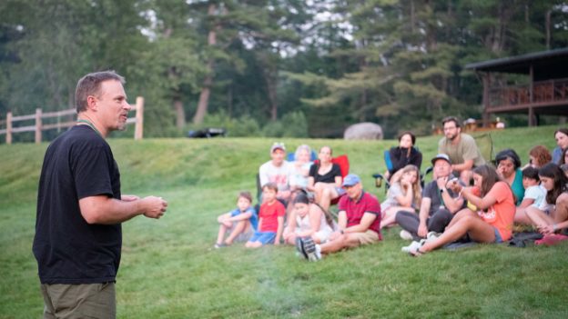 A man speaking to campers outside.