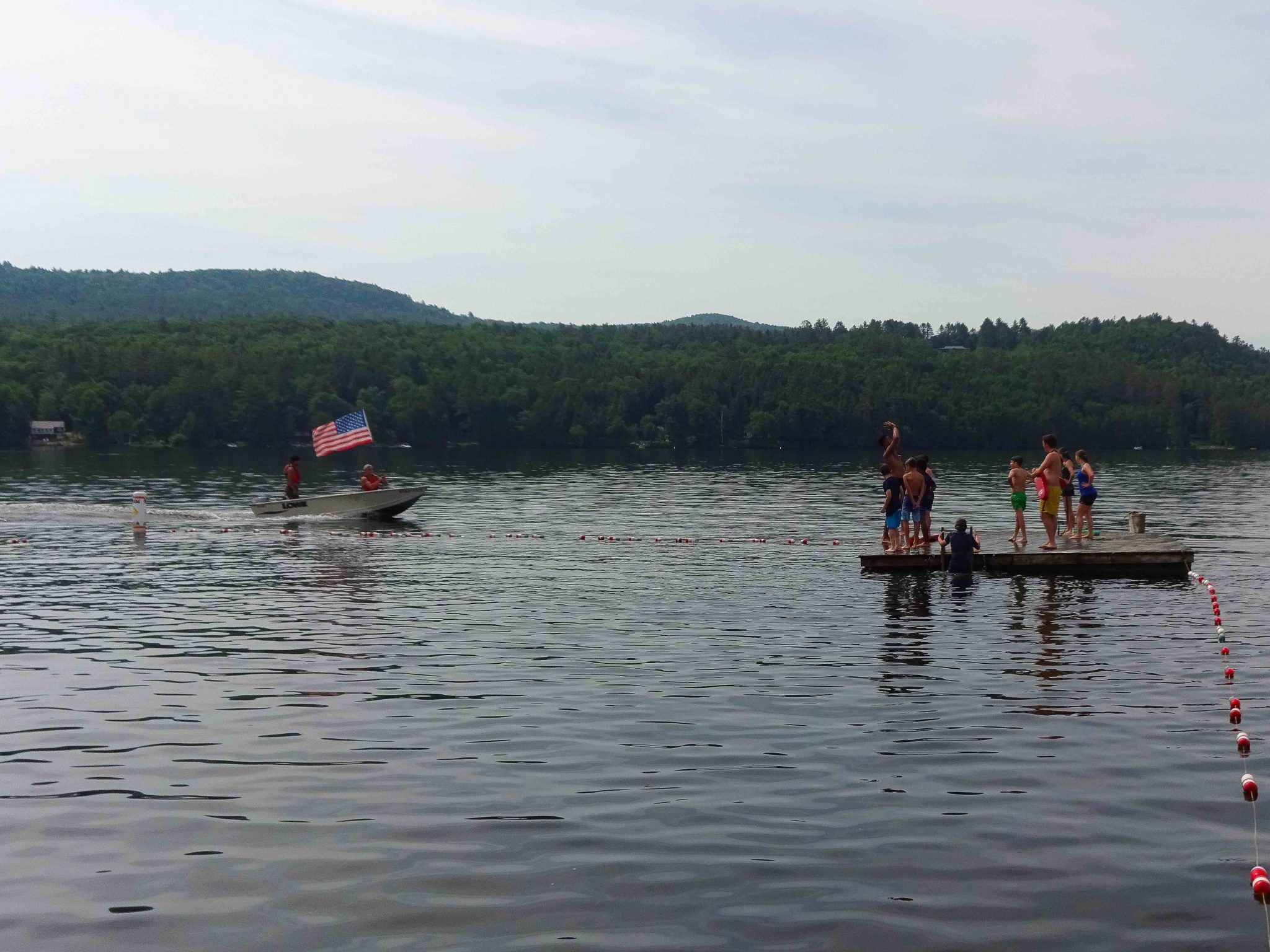 A Horizons group gathered on the floating docs while a motor boat with an American flag drives by.
