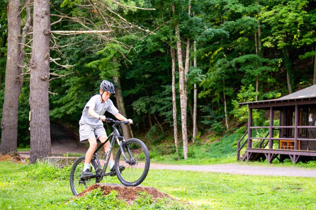 Lanakila camper riding his bike over a stump.