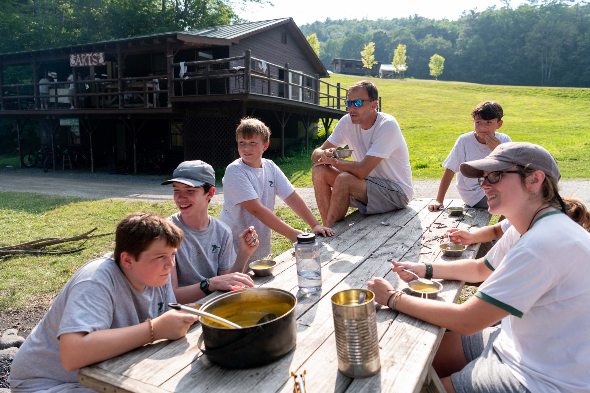 A group of Lanakila campers and counselors with Ridge eating soup they made over a fire.