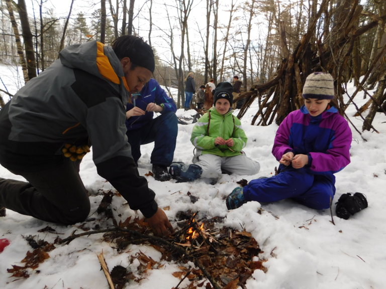 Campers building a fire in the snow.
