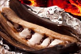 A banana boat being cooked in tin foil on a camp fire.