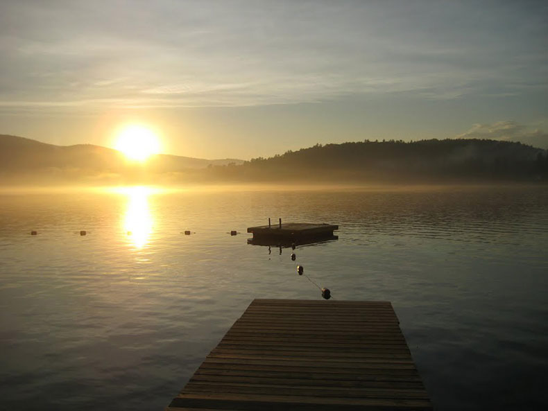 The sun rising over the mountains overlooking the lake.