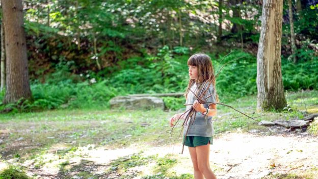 A young Hiver holding a bunch of twigs.