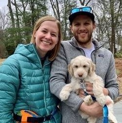 Maggie Finn and Matthew Barnes standing next to each other holding a puppy.