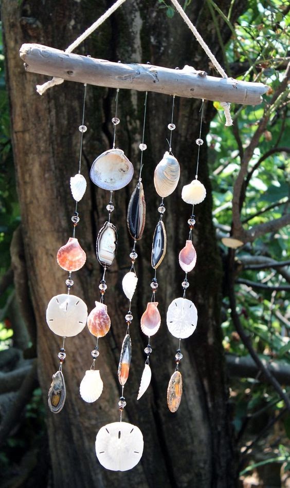 A mobile hung with a tree with a bunch of seashells.