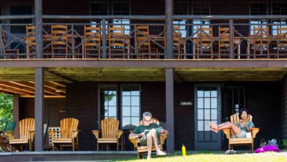 Two people relaxing on lawn chairs in front of a lodge.