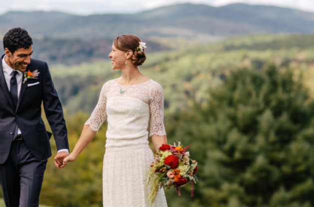A couple celebrating their wedding holding hands outside.