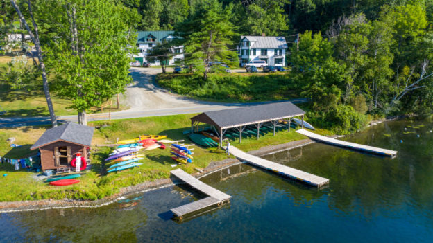 An aerial view of a boathouse and docks in front of a lake.
