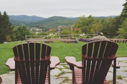 Two lawn chairs with a view of an outdoor wedding set up.