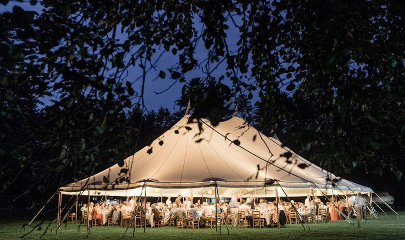 A large white tent over guests sitting at tables.