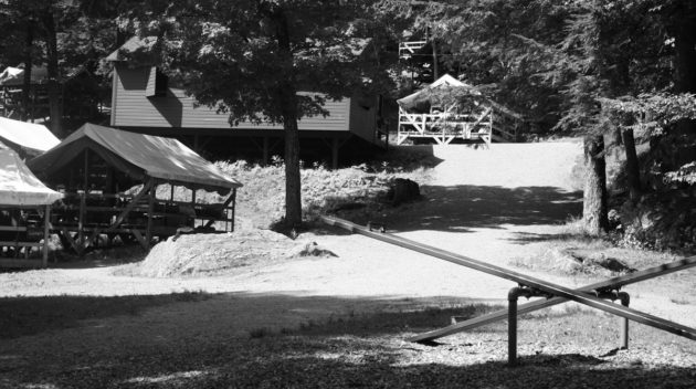 A black and white view of a seesaw and an open air cabin.