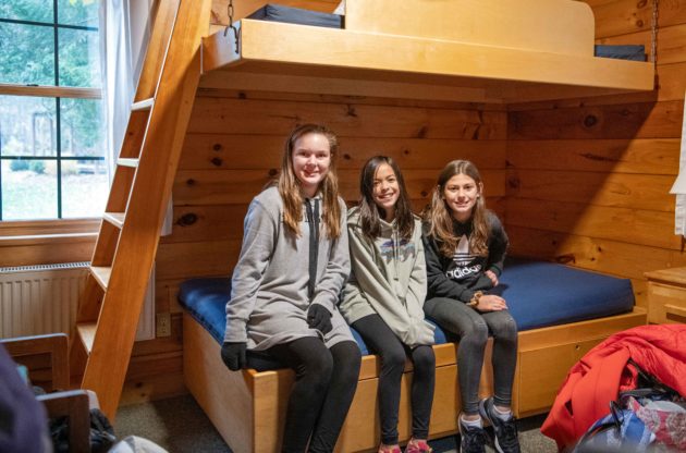 Three girls sitting on one of the bunks in the Hulbert cabin.