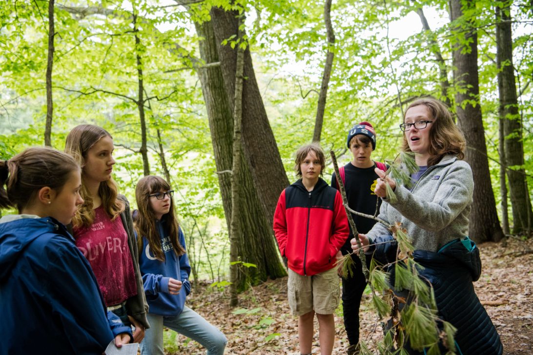 An instructor showing students a tree branch.