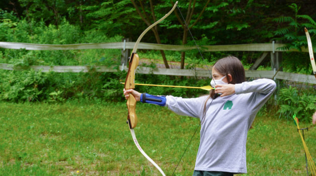 A camper learning how to shoot an arrow.