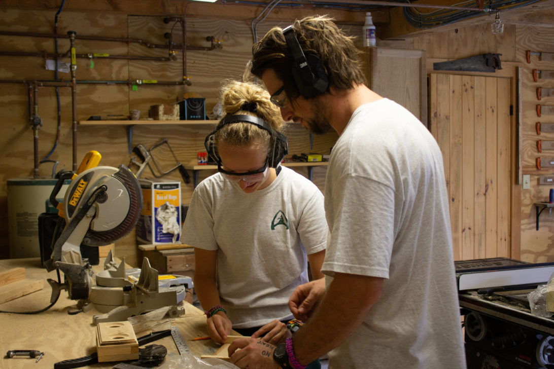 A camper and counselor in woodshop.