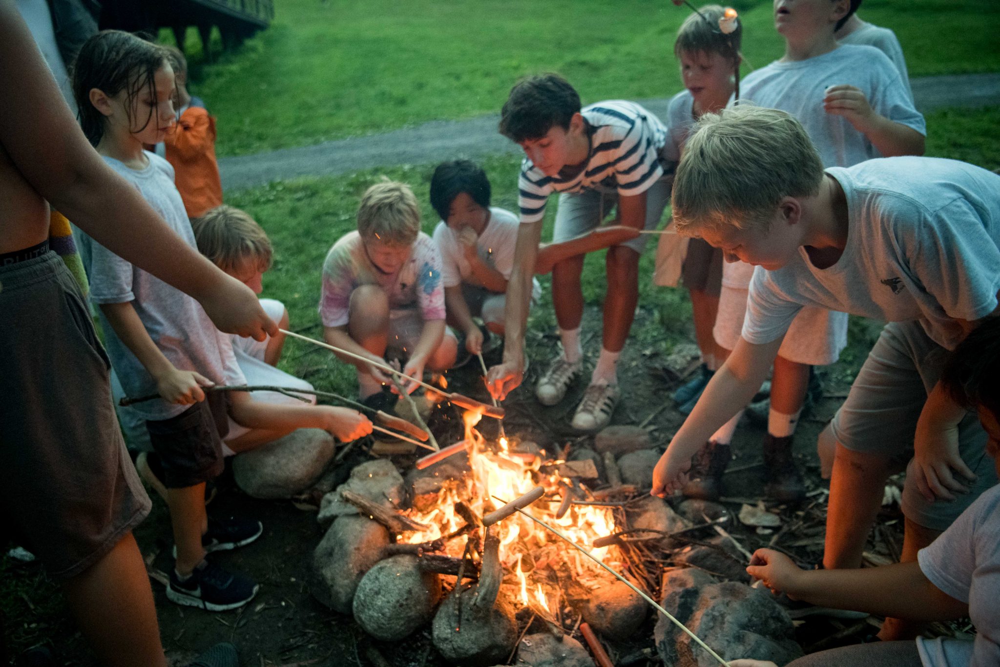 A group of Lanakila campers roasting hotdogs over a fire.