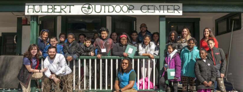 A school group and Hulbert staff gathered on the front porch of The Hulbert Outdoor Center.