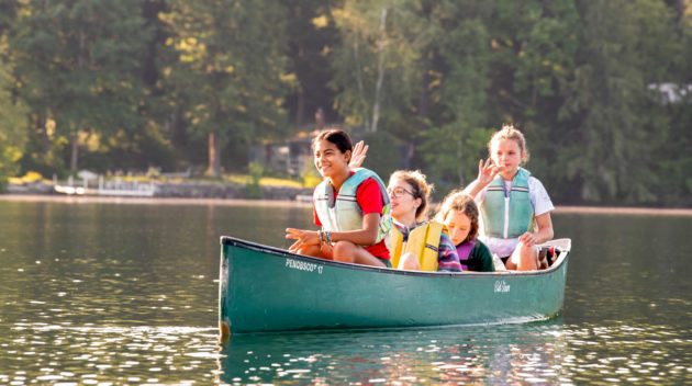 A group of four campers on a canoe together.
